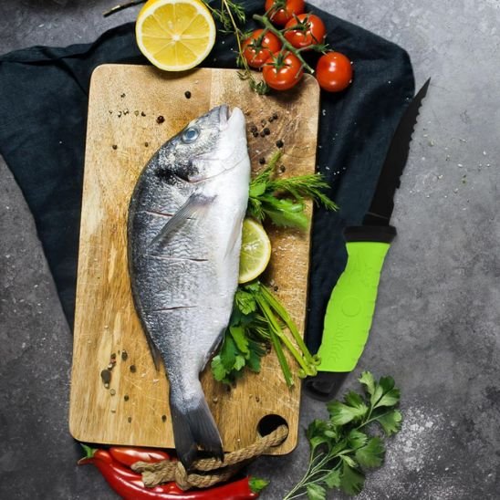 couteau de cuisine a cote de poisson et légumes sur planche de bois