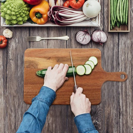 personne coupe concombre sur planche à découper bois