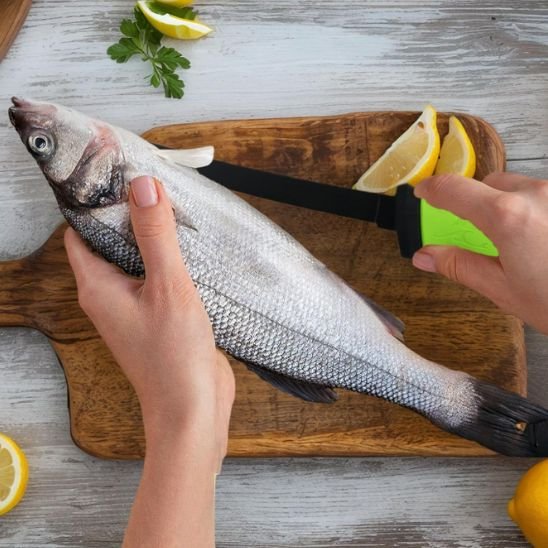 personne tient un poisson d'une main et avec couteau de cuisine coupe le poisson
